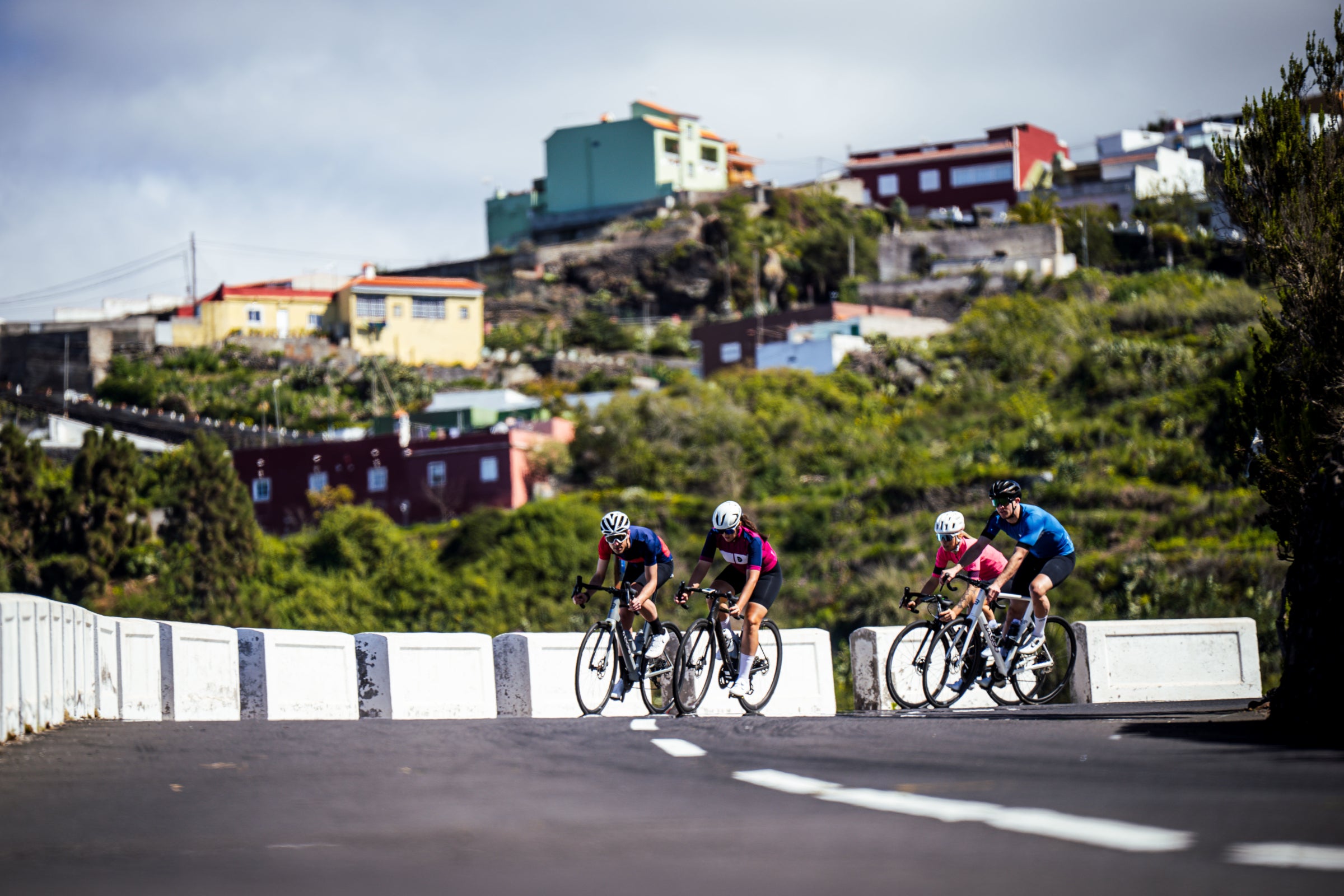 Cyclists riding on a mountain road with colorful houses in the background