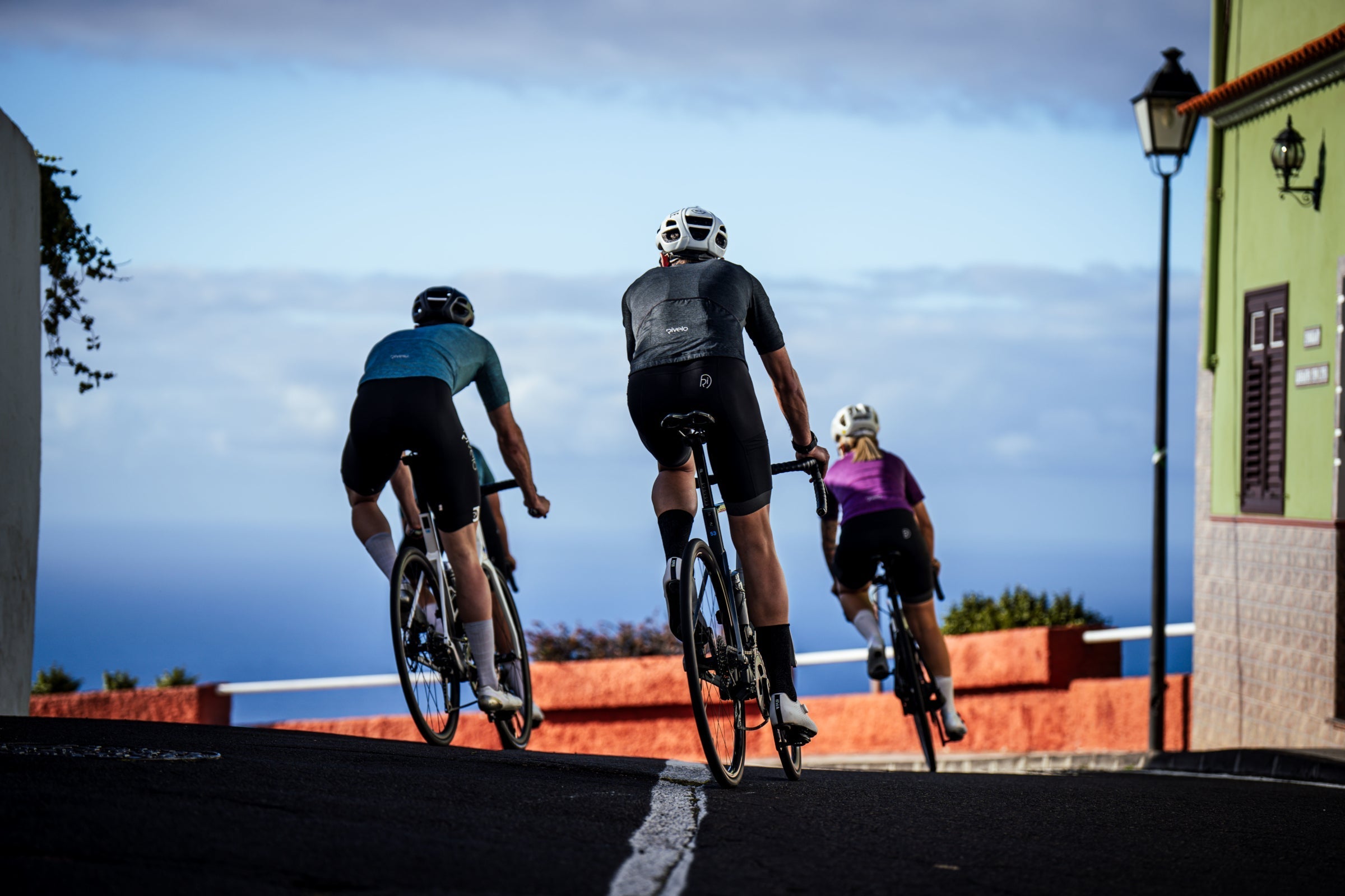 Three road cyclists riding on a coastal street