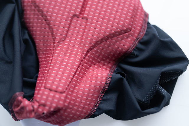 Close-up of a red padded cycling short insert with textured stitching and black fabric edge
