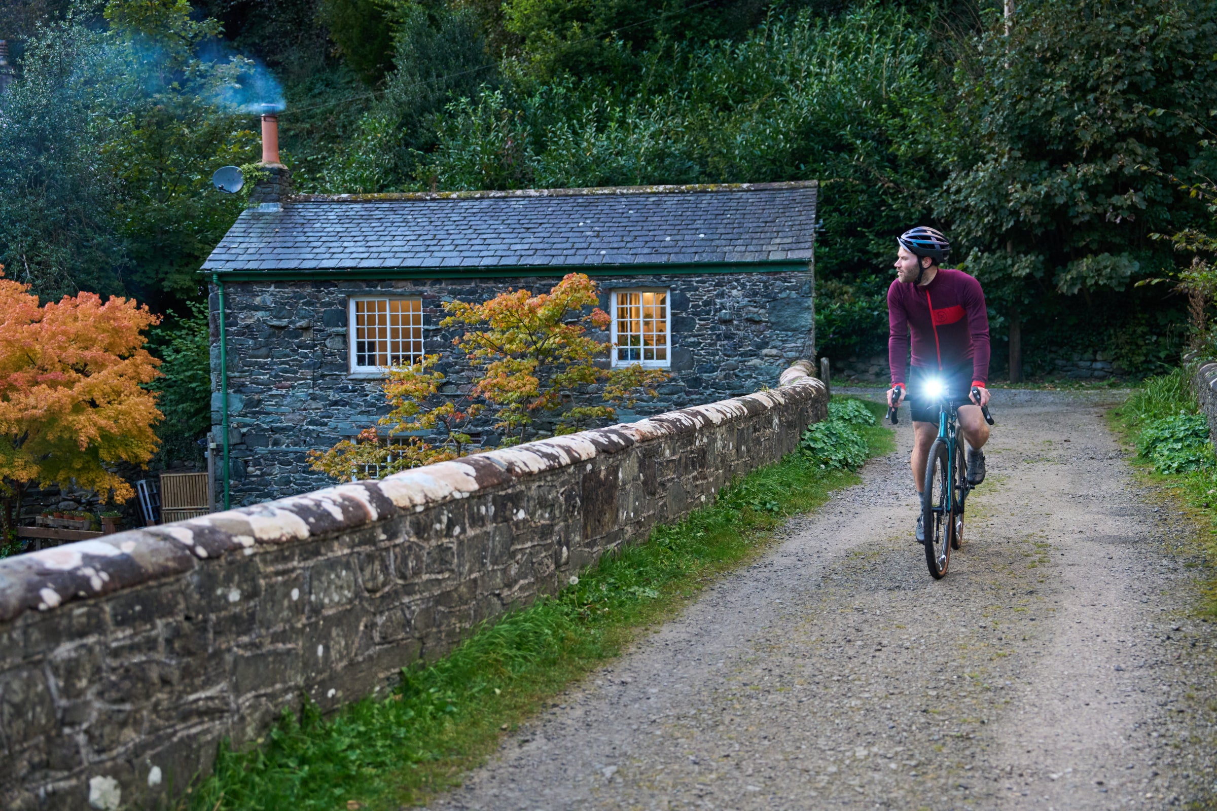 Cyclist riding past a stone cottage
